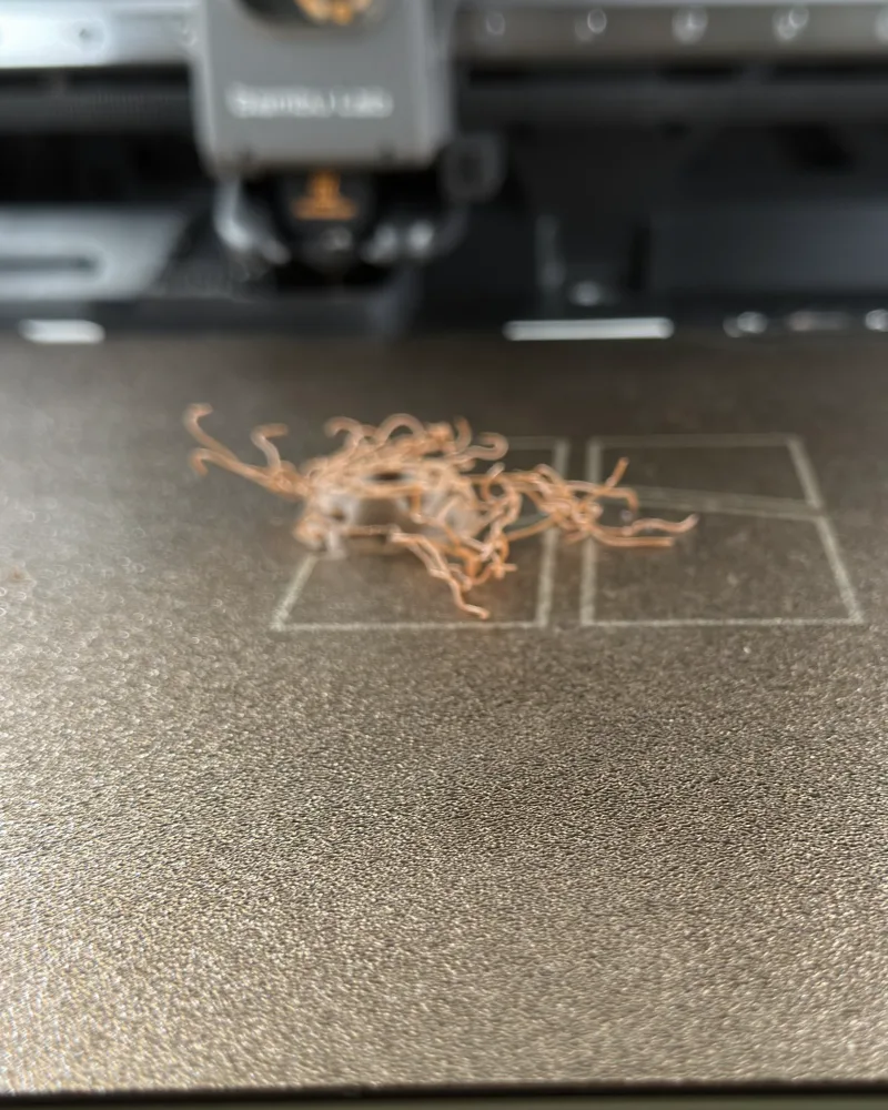 Стол 3D‑принтера с клубком пластиковых нитей там, где печатался оторвавшийся наконечник